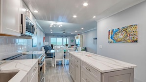 A modern kitchen with a central island, white cabinetry, and a view to the outside.