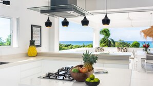 A modern kitchen with a central island, a gas stove, and a view of the ocean. - Fabulous Experience AC, Gym, Chef and Staff Available  (Las Terrenas)