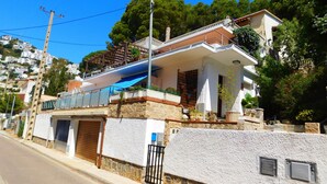 A residential building with a stone facade, a wooden balcony, and a blue awning.