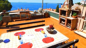 A rooftop terrace with a dining table set for four, overlooking a coastal view.