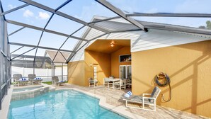 Una piscina interior con techo de cristal, rodeada de sillones de descanso y una pequeña mesa.
