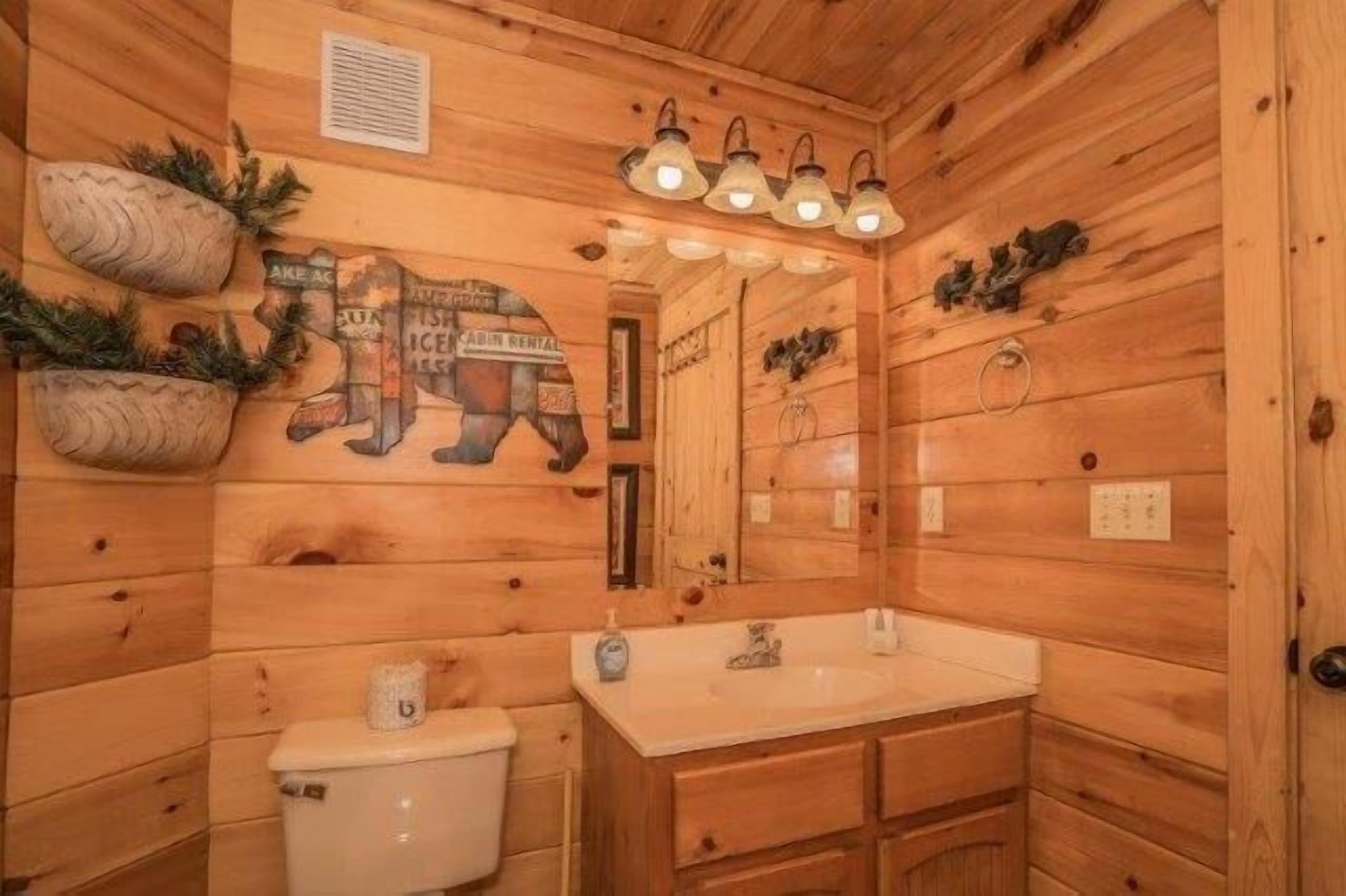 Ein Badezimmer einer Holzhütte mit Waschbecken, Toilette und Spiegel.