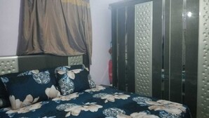 Un dormitorio con cama, armario y cortina.
