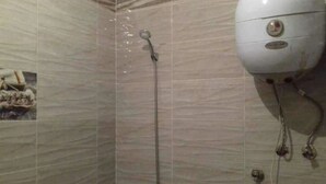 Ducha con cabezal de ducha de mano y panel de control en la pared.