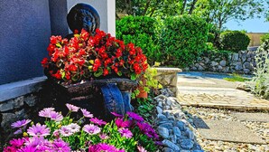 Un jardín con una estatua, flores coloridas y un sendero de piedra.