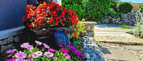A garden with a statue, colorful flowers, and a stone pathway.
