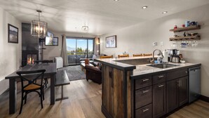 A modern kitchen with a central island, built-in cabinets, and a dining area with a bench. - Modern Edelweiss 2 bedroom Condo! Fantastic views and some of the best ski access!! (Whitefish)