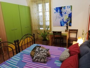 A bedroom with a bed, a desk, a chair, and a green wardrobe.