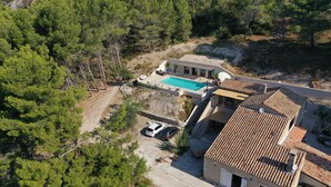 A modern villa with a swimming pool, surrounded by dense pine trees.