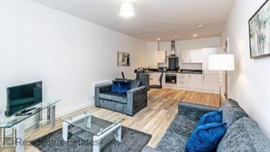 Una sala de estar moderna con un sofá, una mesa de centro de vidrio y un televisor sobre un mueble.