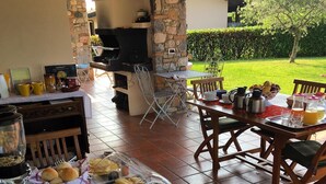 Un buffet de petit-déjeuner en plein air proposant une variété de plats, une cheminée en pierre et une vue sur le jardin.