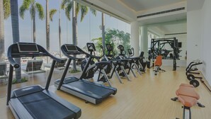 Ett gym med löpband, styrketräningsmaskiner och en träningsbänk.