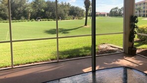 Vista de um quarto com grandes janelas para um campo de golfe.