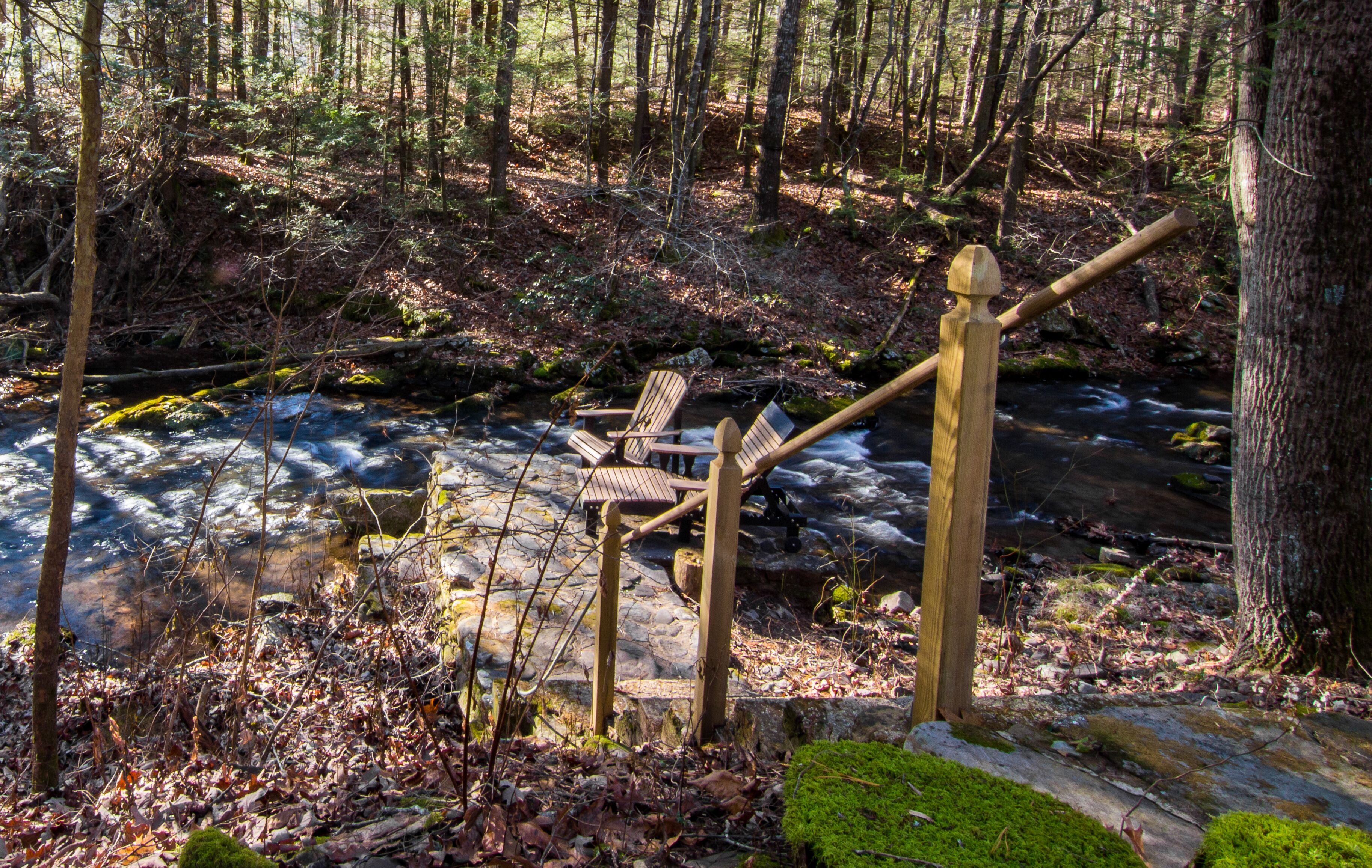 Eine Holztreppe führt zu einem Bach in einem bewaldeten Gebiet hinab.