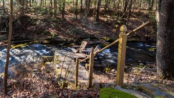 Eine Holztreppe führt zu einem Bach in einem bewaldeten Gebiet hinab.