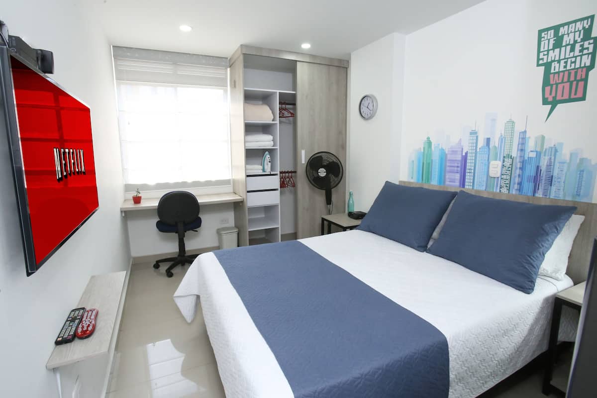 Un dormitorio con cama, escritorio, silla, armario, reloj y una decoración en la pared.