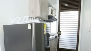 A compact kitchen with a refrigerator, a microwave, and a sink. - Studio Apartments E3 (Medellín)