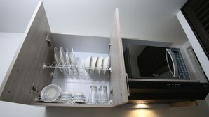 A kitchen with a built-in microwave and a dish rack with plates and glasses. - Studio Apartments E3 (Medellín)