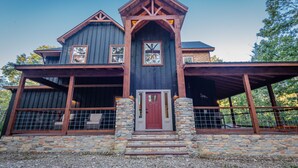 A two-story house with a stone foundation, wooden beams, and a red door.