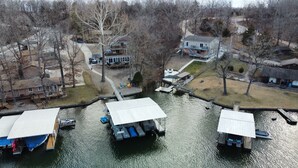 Une propriété au bord du lac, avec des bateaux amarrés, un hangar à bateaux couvert et un petit chalet.