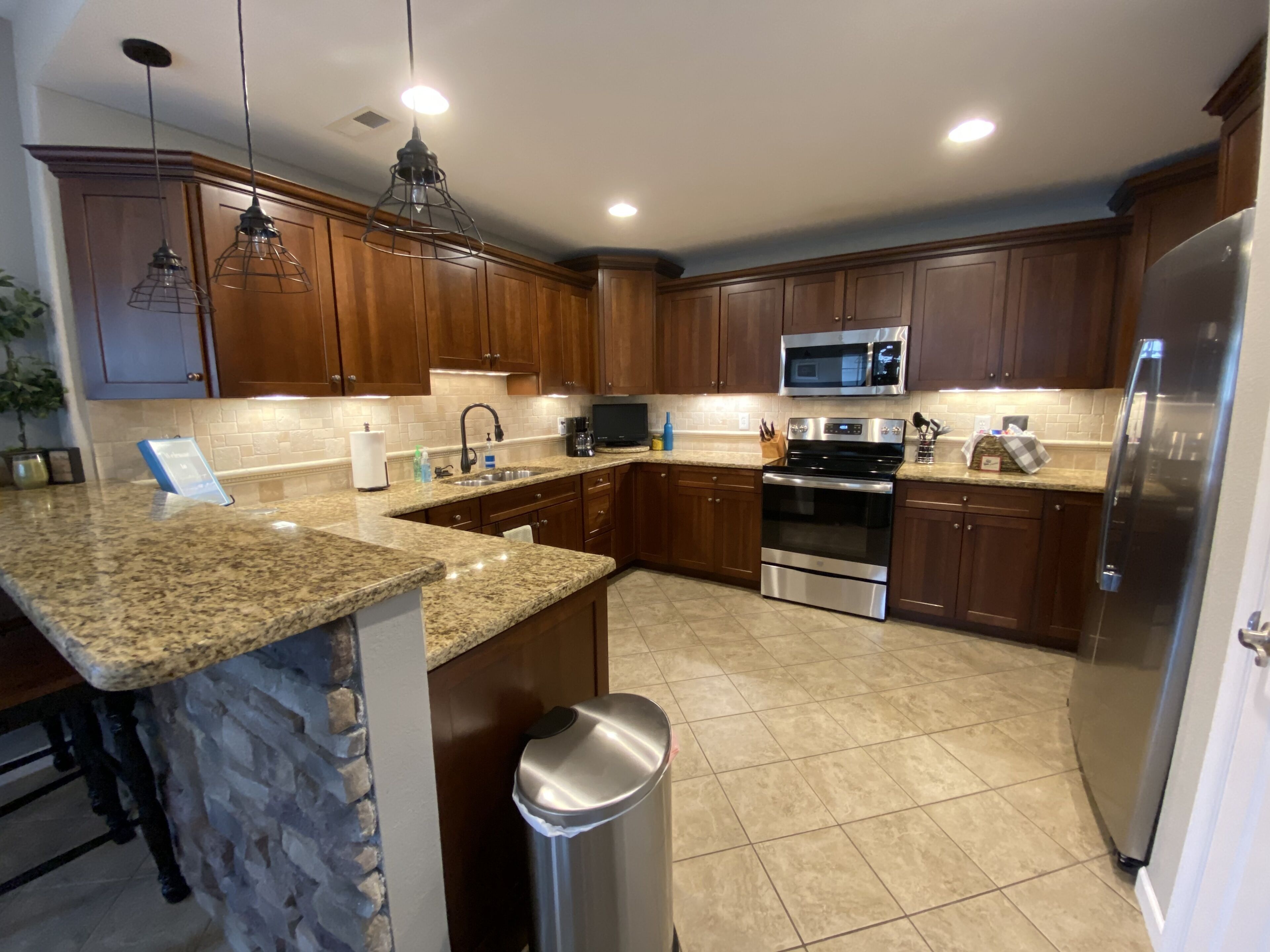 A modern kitchen with granite countertops, stainless steel appliances, and wooden cabinets.
