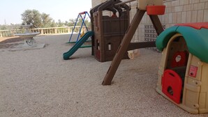 A playground with a slide, climbing structures, and a sandpit.