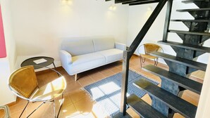 Un intérieur moderne avec un escalier, un canapé blanc et deux fauteuils.