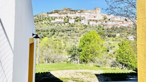 Une vue depuis un couloir, filmée avec une caméra, qui donne sur une cour intérieure et, au loin, sur une colline où se trouvent des bâtiments et un château.