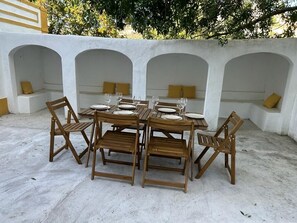 Een terras met een witte muur en een boogvormige zithoek.