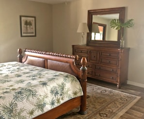 A bedroom with a bed, a dresser, a mirror, and a framed picture on the wall. - River House - Overlooking the Scenic Withlacoochee River - Sleeps 4. (Inglis)