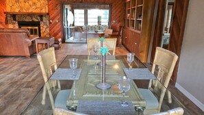 A dining area with a glass table, wicker chairs, and a stone fireplace. - River House - Overlooking the Scenic Withlacoochee River - Sleeps 4. (Inglis)