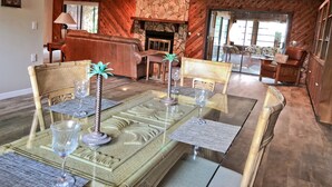 A dining area with a glass-top table, chairs, and a stone fireplace. - River House - Overlooking the Scenic Withlacoochee River - Sleeps 4. (Inglis)