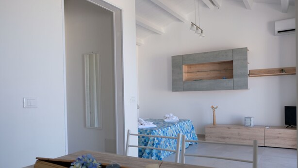 A modern room with a wooden dining table, a blue and white checkered tablecloth, a wooden cabinet, and a mounted TV.