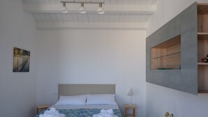 A bedroom with a bed, two bedside tables, a wall-mounted shelf, and a painting on the wall.