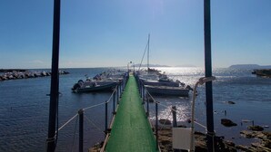 A pier leading to boats docked at a marina with a clear sky.