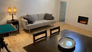 A cozy living room with a sofa, a dining table with chairs, a pool table, and a fireplace. - House by the Castle (360 panoramic View) (Castelo de Vide)