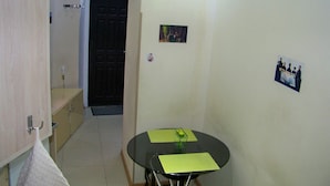 Une petite pièce isolée, dotée d’une porte, d’une table recouverte d’un set de table vert et d’une serviette accrochée à la porte.