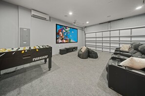 A room with a foosball table, a TV, bean bags, and a massage chair. - Charming Oasis with Home Theater at Encore (Kissimmee)