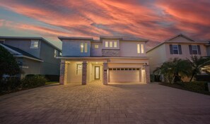 A modern two-story house with a garage, a driveway, and a well-maintained lawn. - Charming Oasis with Home Theater at Encore (Kissimmee)