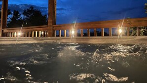 Un espace avec un bain à remous, doté de rampes en bois, offrant une vue sur le ciel au crépuscule.