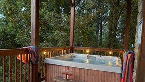 Un bain à remous sur une terrasse en bois, avec des bancs et des serviettes.