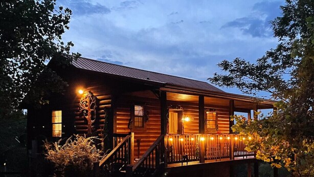 Une cabane en rondins avec une véranda, des marches en bois et une balustrade.