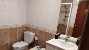 Une salle de bain avec deux toilettes, un lavabo et une douche.