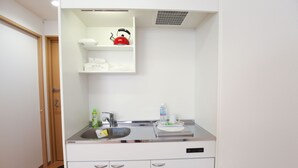 A compact kitchenette with a sink, a kettle, and a microwave.