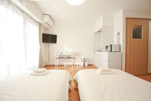 A hotel room with two beds, a desk with chairs, a television, a microwave, and a door. - Connect Inn (Osaka)