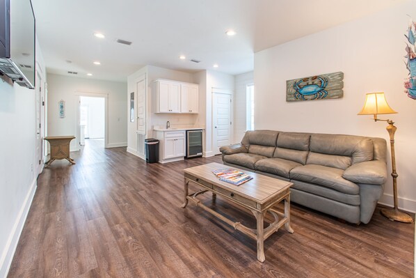 A spacious living room with a leather sofa, a wooden coffee table, and a lamp.