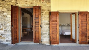 Ein rustikales Steinhaus mit Holztüren, das zu einem Essbereich und einem Schlafzimmer führt.