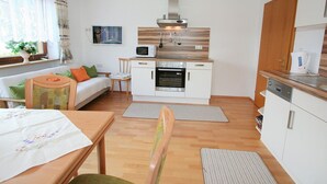 A compact kitchen with a microwave, oven, and coffee maker. There is a dining area with a table and chairs, and a sofa with cushions. - Beautiful apartment for 4 guests with WIFI, TV, terrace and panoramic view (Fügen)