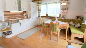 A compact kitchen with white cabinets, a wooden countertop, and a dining area with a table and chairs. - Beautiful apartment for 4 guests with WIFI, TV, terrace and panoramic view (Fügen)