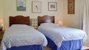 Ein Doppelbett mit Holz-Kopfteil, zwei Nachttische und ein Beistelltisch mit Lampe.